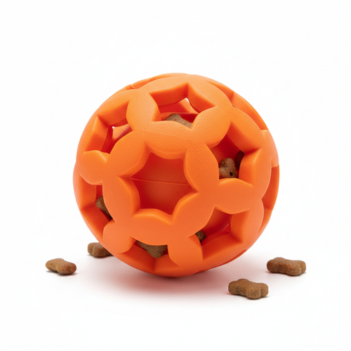 Orange rubber treat dispensing ball toy for dogs with small bone-shaped treats scattered around
